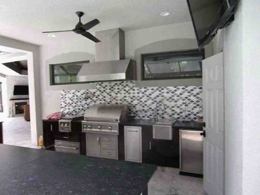 Covered outdoor kitchen with built-in grill and mosaic backsplash, North Tampa custom home